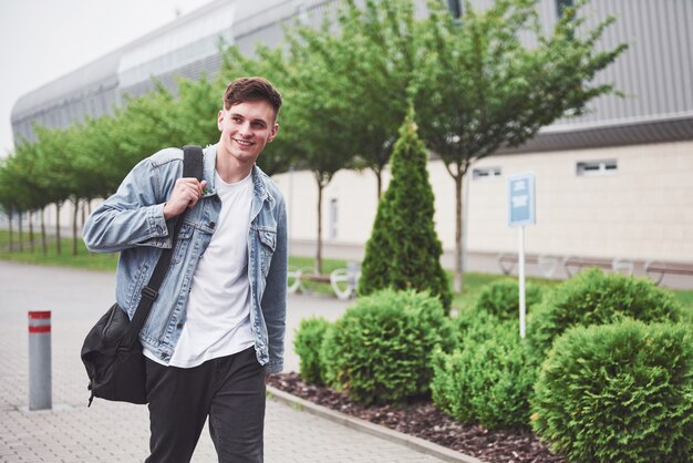 Young handsome man with a bag on his shoulder in a hurry to the airport.