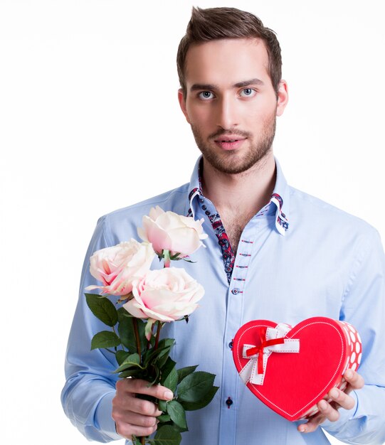 Young handsome man with a pink roses and a gift - isolated on white