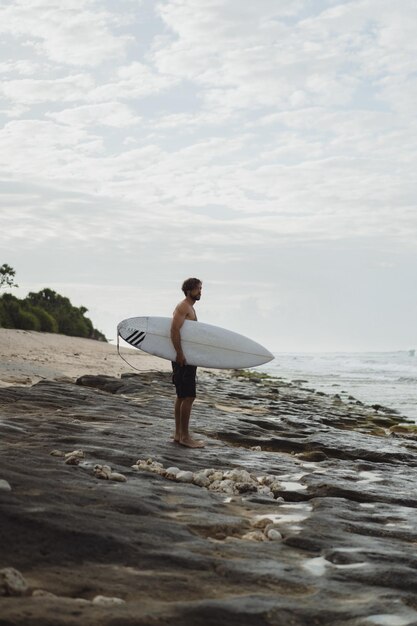 Young handsome man with a surfboard on the ocean.