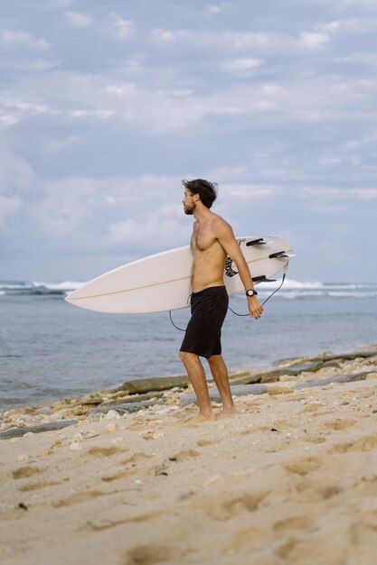 Young handsome man with a surfboard on the ocean.