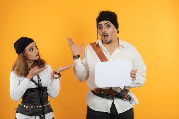 Young handsome pirate holding idea board and female pirate Point hand to him. High quality photo