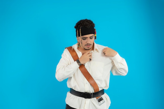 Young handsome pirate looking down and straighten his shirt. High quality photo