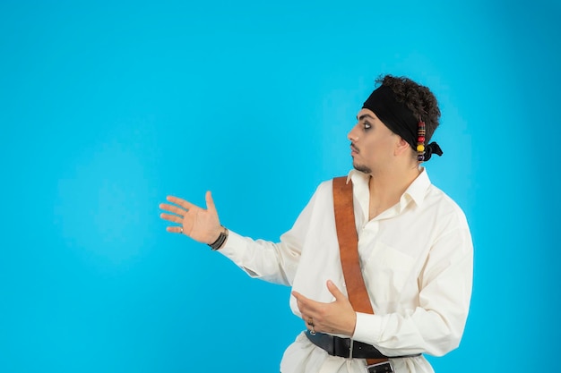 Young handsome pirate looking at side and point hand to the right side. High quality photo