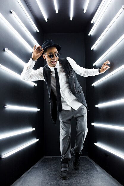 Young handsome smiling hipster black man in retro vintage style suit dancing hip hop in disco night club, having fun