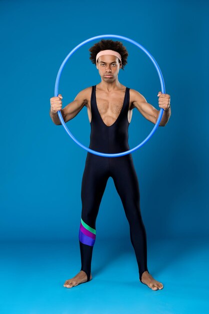 Young handsome sportive african man posing with hoop on blue