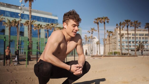 Young handsome sporty man with wireless earphones resting during workout outdoor