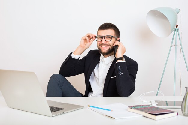 young handsome stylish hipster man in young jacket sitting at office table