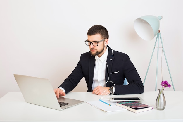 Young handsome stylish hipster man in young jacket working at office table