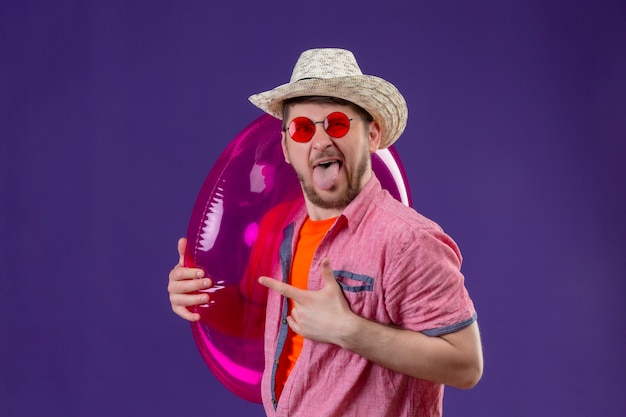 Young handsome traveler man in summer hat with inflatable ring