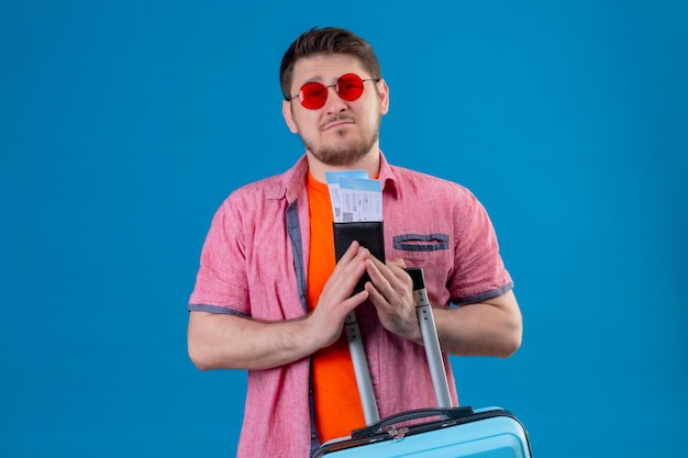 비행기 티켓과 가방을 들고 선글라스를 착용하는 젊은 잘 생긴 여행자 남자