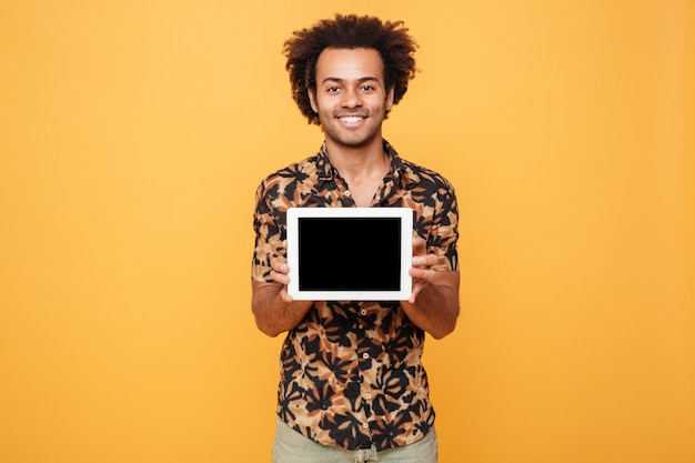 Foto gratuita giovane uomo afroamericano felice che mostra la compressa del pc dello schermo in bianco