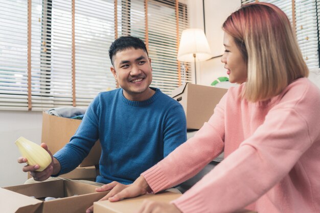 그들의 새로운 가정으로 이동하는 젊은 행복 아시아 부부, 오래된 집에서 오래된 물건을 확인하기 위해 상자 열기