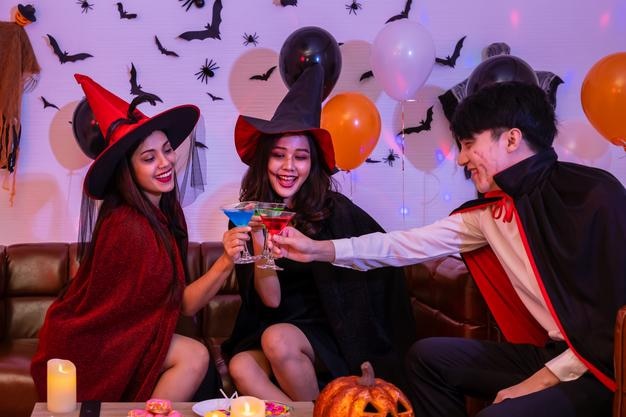 젊은 행복한 아시아 사람들이 할로윈 의상을 입고 뱀파이어와 마녀 파티에서 축하하는 와인 잔을 들고 부딪친다