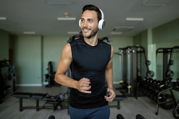 Young happy athlete jogging on running track in health club