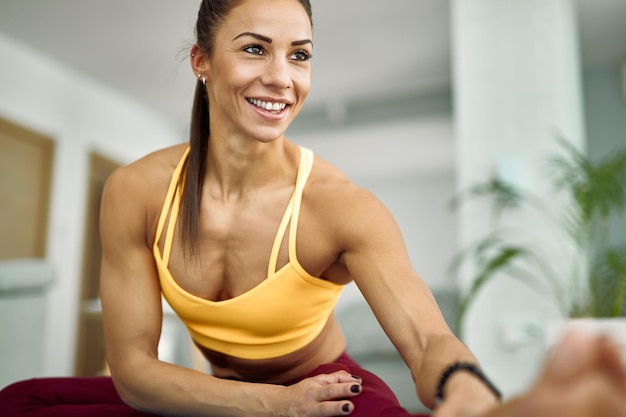 Young happy athletic woman doing stretching exercises while working out at home