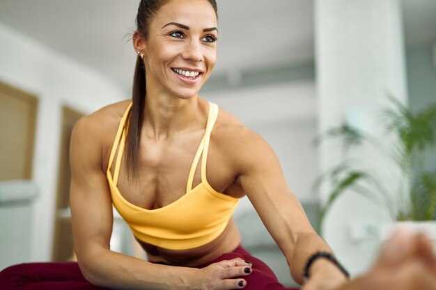 Молодая счастливая спортивная женщина делает упражнения на растяжку во время тренировки дома