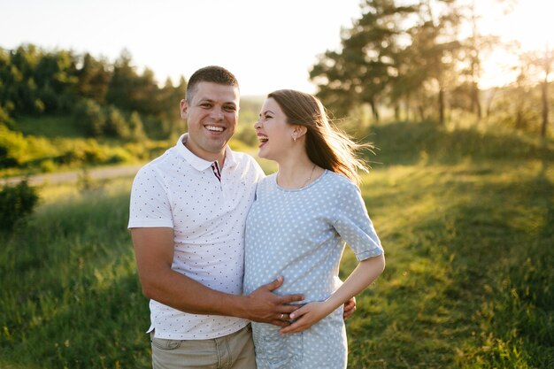 young happy beautiful couple in love walking together on grass and trees park landscape