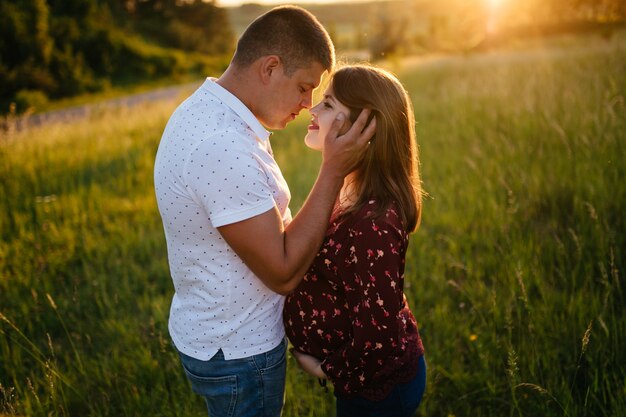 young happy beautiful couple in love walking together on grass and trees park landscape