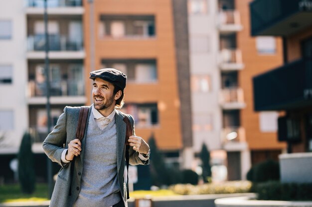 街を歩いているバックパックを持つ若い幸せなビジネスマン