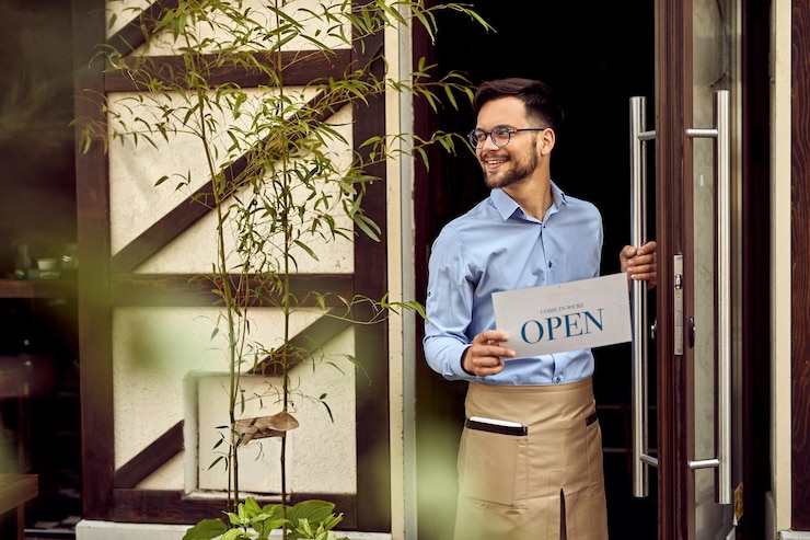 Free Photo young happy cafe owner opening for business and hanging open sign at entrance door