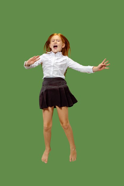 緑のスタジオの背景に分離された、空中でジャンプする若い幸せな白人の十代の少女。美しい女性の半身像。