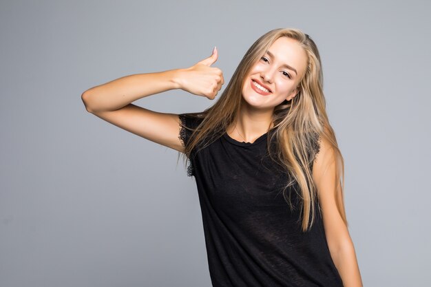 Young happy cheerful woman showing thumb up isolated on gray background