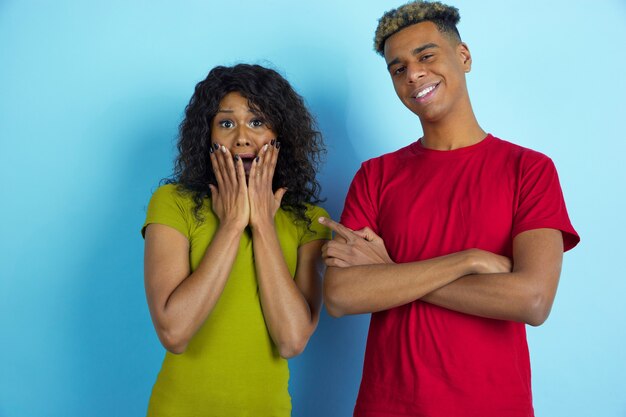 Young happy couple in casual clothes posing on blue wall