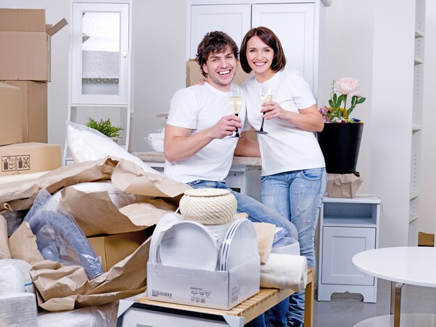 Young happy couple celebrating new home together with glass of champagne - indoors