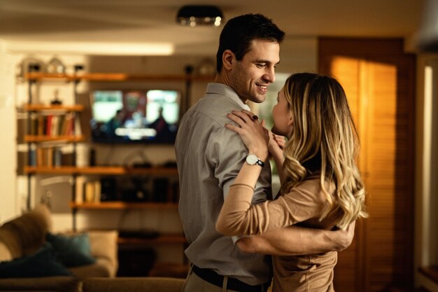 Молодая счастливая пара танцует в гостиной