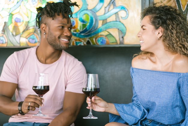 젊은 행복한 커플은 와인 한 잔을 마시고 레스토랑에서 데이트를 하면서 함께 좋은 시간을 즐기고 있습니다.