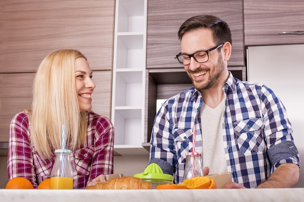 Молодая счастливая пара пьет свежий апельсиновый сок на кухне