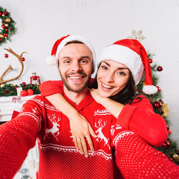 Молодая пара счастлива, охватывающей в рождественские шляпы
