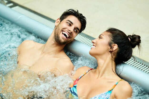 웰빙 센터에서 물에서 휴식을 취하면서 재미와 의사 소통을 하는 젊은 행복한 커플
