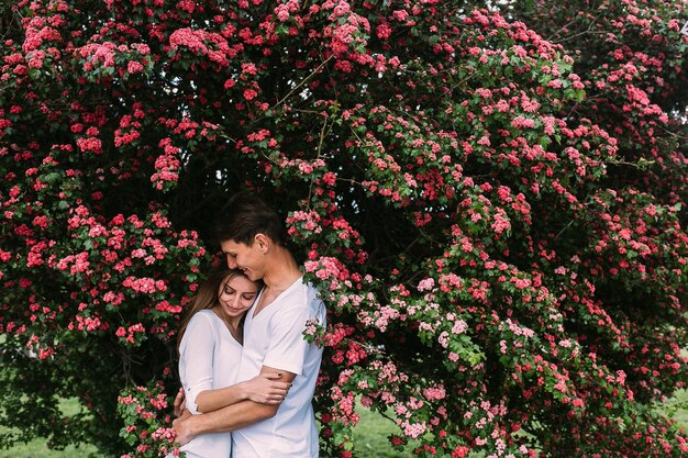 Молодая пара счастлива в любви на открытом воздухе. любящие мужчина и женщина на прогулке в весеннем цветущем парке