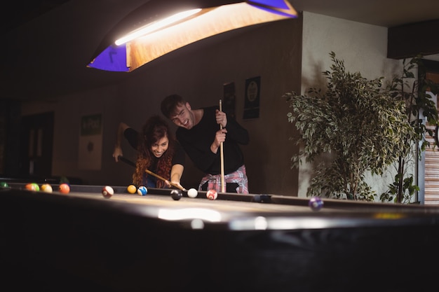 Free photo young happy couple playing pool