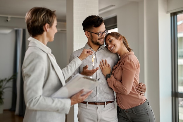 Young happy couple receiving keys of their new home from real estate agent