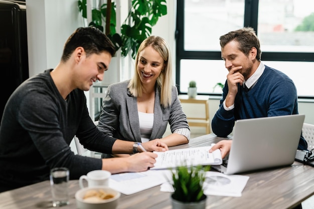 Young happy couple signing an agreement with real estate agent on a meeting in the office