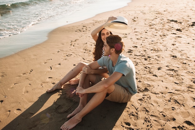 Free photo young and happy couple sitting next to the sea