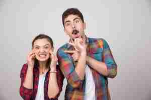 Free photo young happy couple standing and posing on a gray wall.