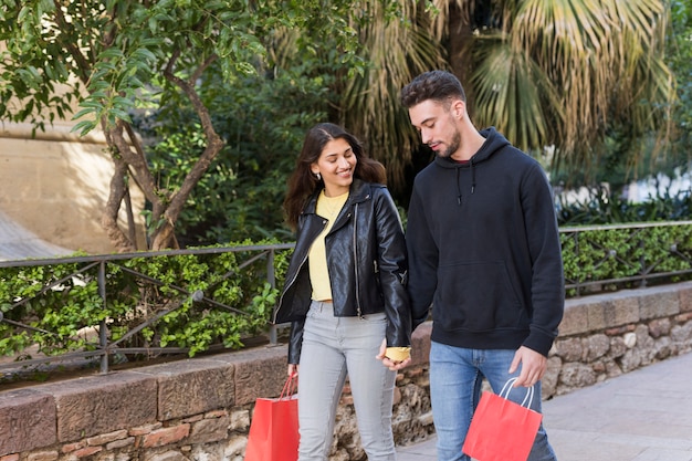 Young happy couple walking on street near trees