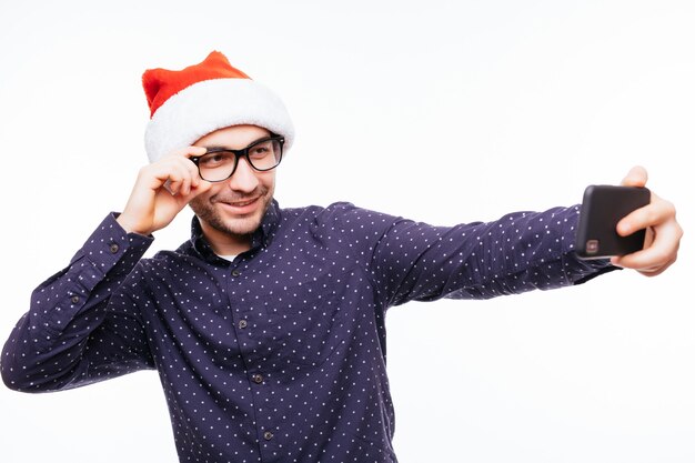 Young happy emotional man wearing christmas santa hat standing isolated over white wall