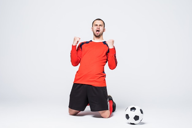 Young happy and excited football player in jersey celebrating scoring goal