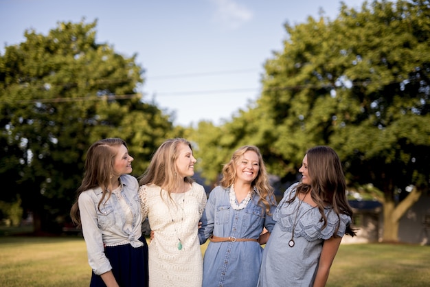 Giovani ragazze felici una accanto all'altra dietro gli alberi