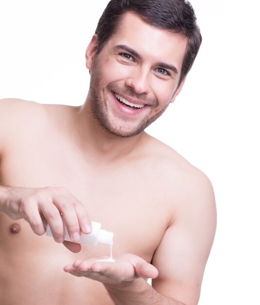 Young happy handsome man pours lotion on his hand - isolated on white.