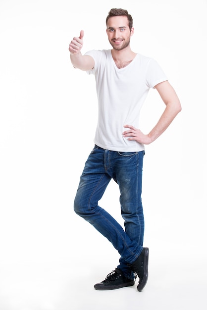 Young happy handsome man with thumbs up sign in casuals in full growth - isolated on white.