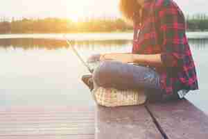 Free photo young happy hipster woman working with her laptop sitting on pie