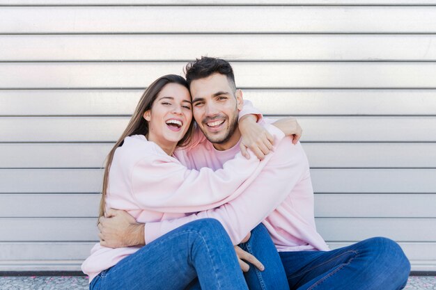 Young happy lady hugging smiling guy 