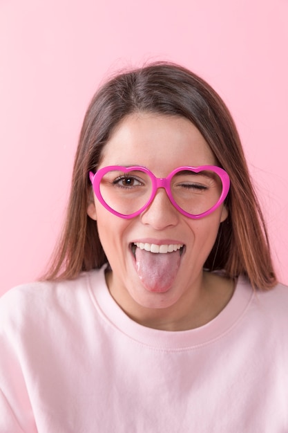 Молодая счастливая дама с очки показывает язык