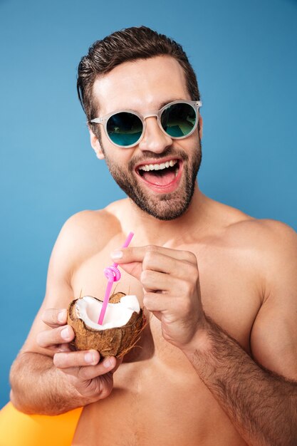 Young happy man holding cocktail from coconut