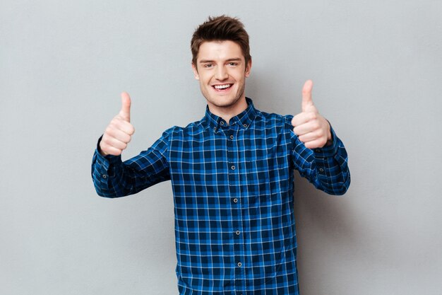 Young happy man holding thumbs up isolated